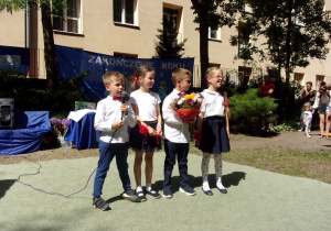 Juniorzy w galowych strojach z kwiatami w podziękowaniu