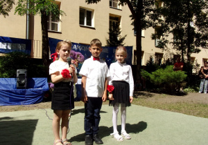 troje dzieci w galowych strojach recytuje wiersz