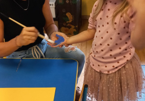 nauczycielka maluje farbą rączkę dziewczynki