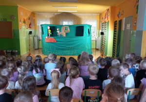 Dzieci oglądają scenę na której znajdują się dwie kukiełki
