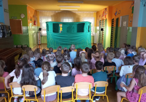 Przedszkolaki oglądają scenę na której znajduję się kukiełka