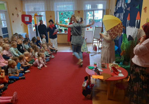 Przedszkolaki przypatrują się pracownikom przedszkola wcielających się w swoje role.