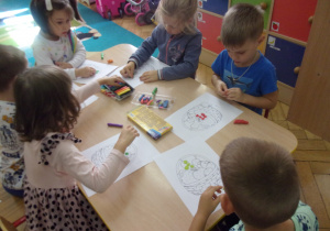 Dzieci pracują przy stolikach.