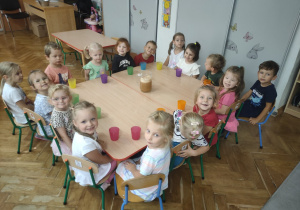 Dzieci siedza przy duzym stole.