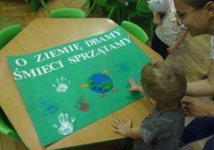 Chłpiec odciska swoje palce na papierze.