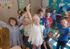 Dzieci stoja razem z rękami w górze.