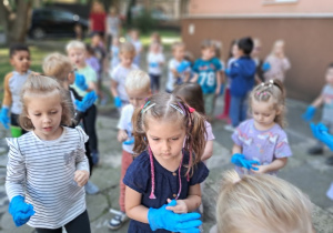 Smyki poszukują śmieci na ogrodzie przedszkolnym.