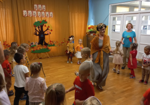 Przedszkolaki przebrani w kolorach jesieni tańczą.