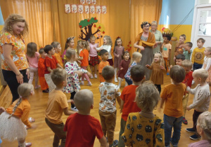 Przedszkolaki przebrani w kolory jesieni tańczą.
