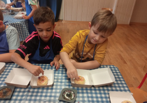 Dzieci dekorują pączki.