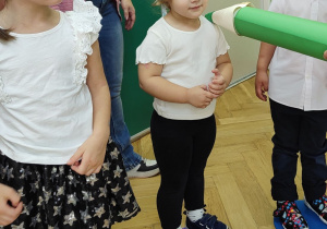 Troje dzieci stoi obok siebie podczas pasowania na przedszkolaka.