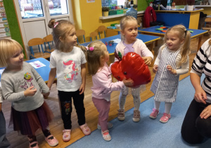 Dziewczynka trzyma balon w kształcie jabłka.