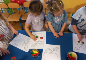 Dzieci kolorują kolorowankę z jabłkiem.