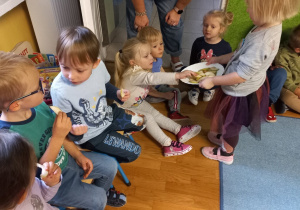 Dziewczynka rozdaje dzieciom jabłka.