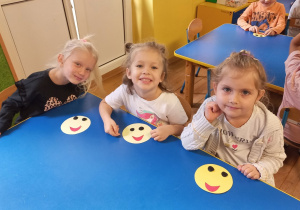 Dziewczynki uśmiechają się ze zrobionymi pracami plastycznymi.