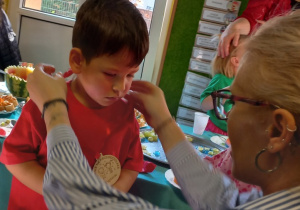 Pani Agnieszka zakłada chłopcu medal.