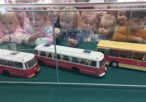 Tuptusie przyglądają się modelom starych tramwajów i autobusów.