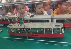 Tuptusie przyglądają się modelom starych tramwajów i autobusów.