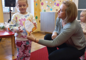 Dziewczynka odbiera nagrodę od Pani Dyrektor.