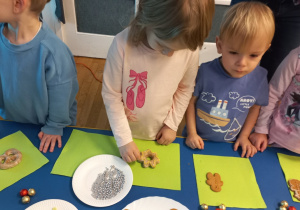 Dziewczynka w bluzce z różowymi balerinkami ozdabia swojego pierniczka.