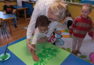 Pani Agnieszka z dziewczynką odbija rękę umalowaną na zielono.