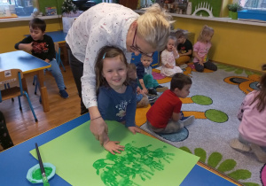 Pani Agnieszka z dziewczynką odbija rękę umalowaną na zielono.