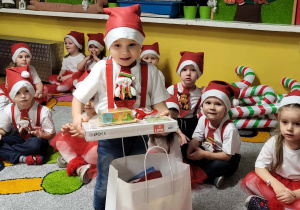 Chłopiec w czapce Mikołaja odbiera prezent.