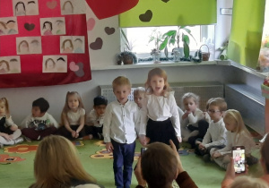 Dziewczynka i chłopiec występują przed gośćmi.
