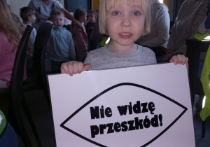 Dziewczynka trzyma kartkę z napisem "Nie widzę przeszkód!".