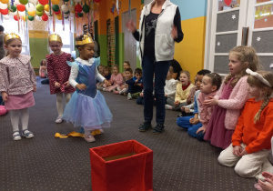 Dziewczynka wrzuca woreczek do czerwonego pudełka.