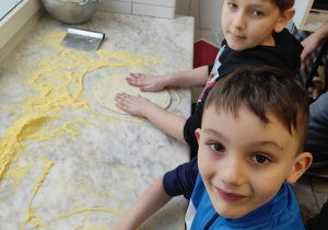 Chłopcy przygotowują ciasto na pizze.