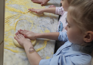 Dziewczynki ugniatają ciasto na pizze.