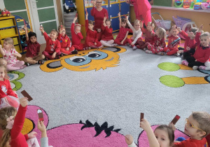 Smyki i Tuptusie siedzą na dywanie w kole.