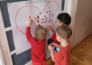 Dzieci przyklejają serca na sercometr.