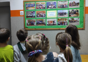 Juniorzy oglądają zdjęcia na tablicy korkowej.