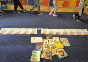 Dzieci chodzą po dywanie pośród książek.