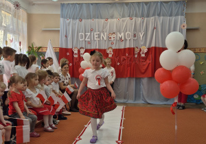 Kolejna dziewczynka idzie wzdłuż sali.