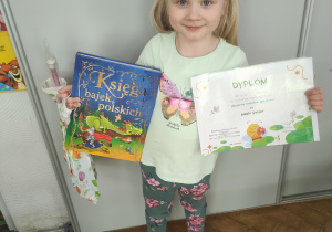 Dziewczynka trzyma w ręku książki.