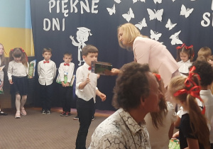 Pani Dyrektor wręcza książkę chłopcu.