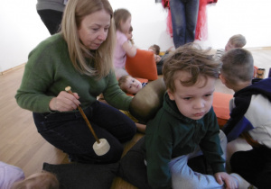 Osoba prowadząca warsztaty uderza w metalową miskę.