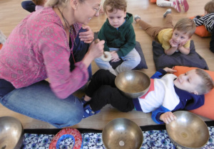 Chłopiec leży z misą metalową na brzuchu.