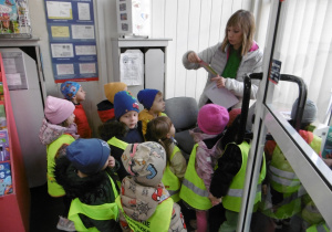 Dzieci i nauczycielka stoją przy oknie w pomieszczeniu poczty.