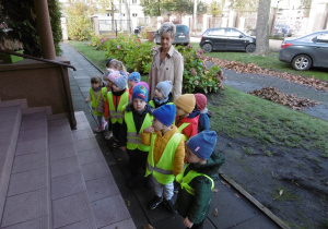 Grupa dzieci razem z panią z obsługi stoją przed wejściem do PM52