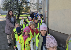 Dzieci idą przy ścianie budynku.