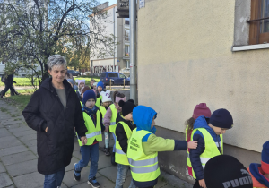 Inna grupa dzieci idzie przy ścianie budynku.