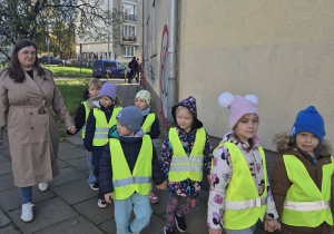 Nauczyciel prowadzi za rękę dziecko.