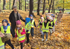 Grupa dzieci idzie aleją parkową.