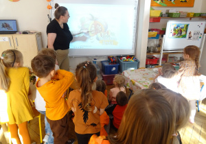 Nauczycielka stoi przy tablicy multimedialnej.