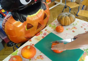 Balon przedstawiający postać z bajki przy stoliku z dyniami.