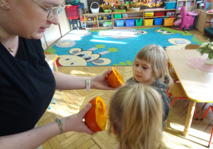 Nauczycielka pokazuje dzieciom przekrojone dynie.